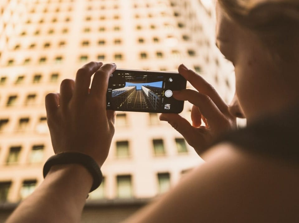 Person fotografiert ein Bürogebäude mit dem Smartphone – Asset-Erfassung mit der picsure-App